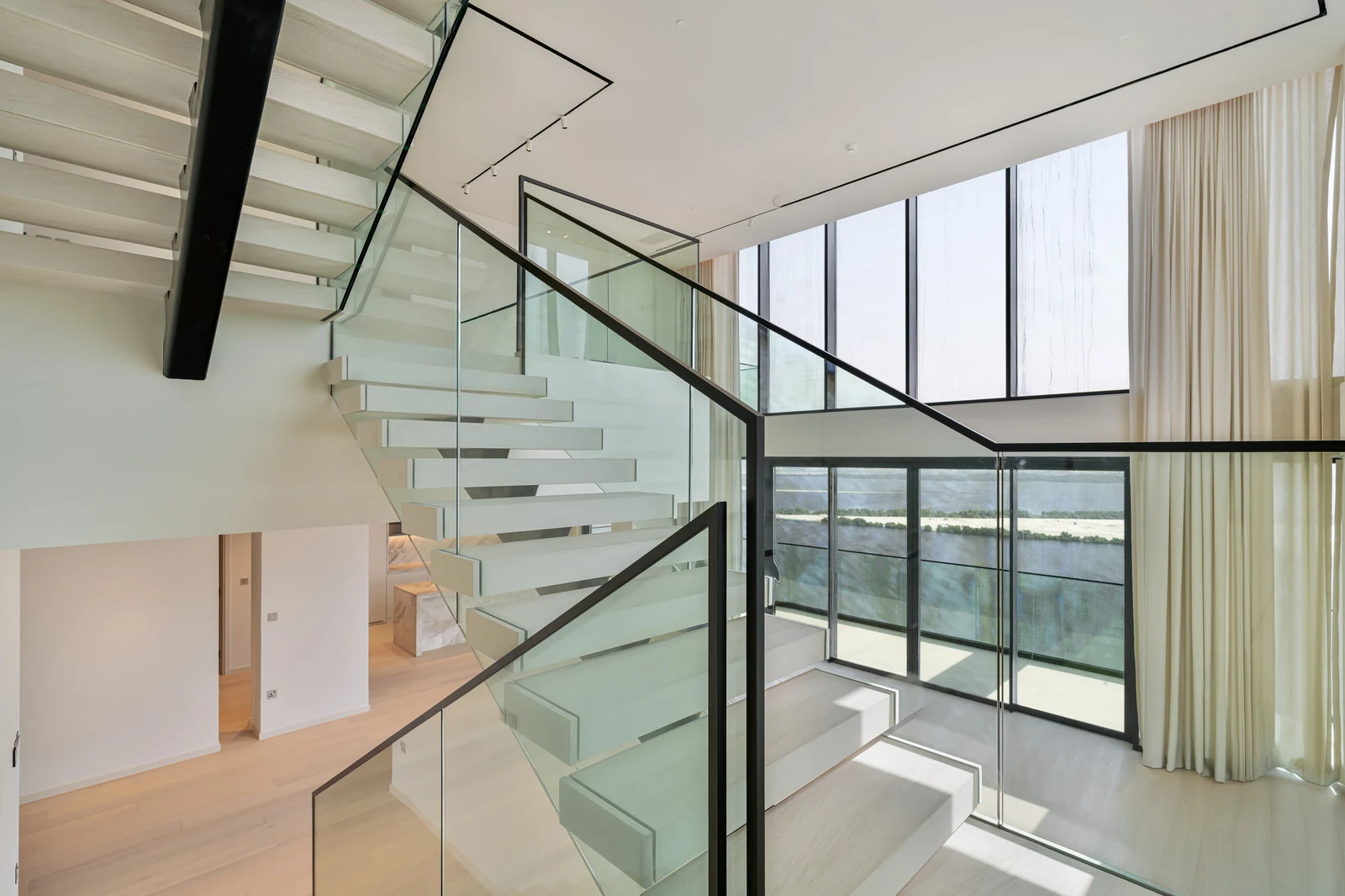 Glass staircase beside the full-height windows