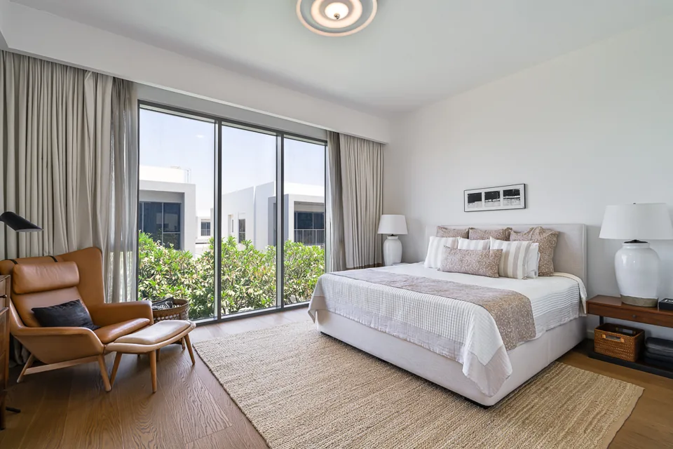 Primary suite with upholstered bed and balcony doors